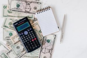 Calculator and notepad placed overstack of usa dollars