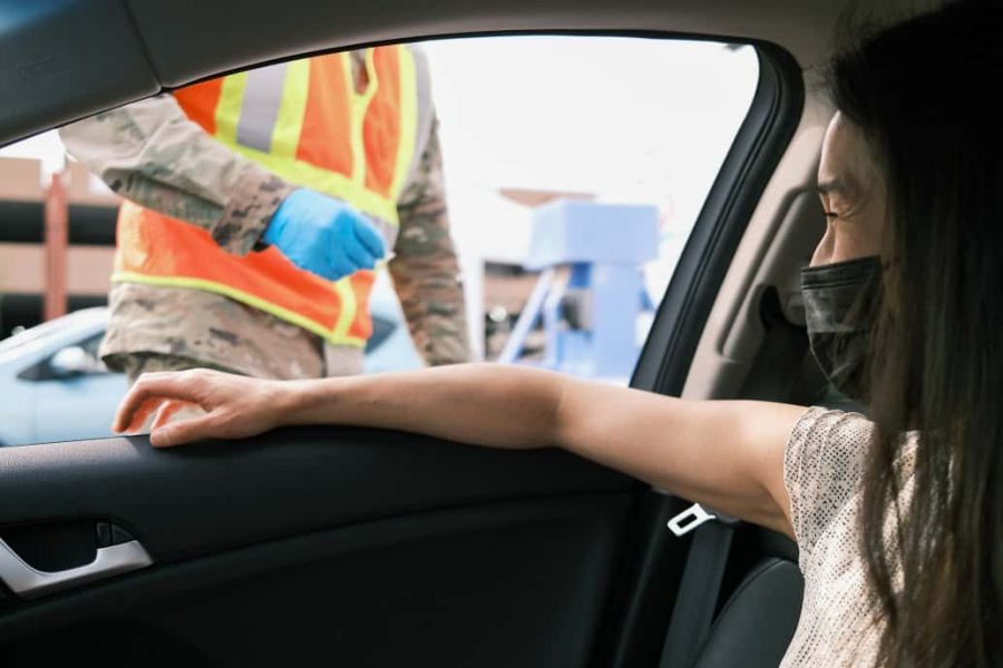 vaccine tourism in the US woman in car streching hand to get covid-19 vaccine at drive thru vaccine location